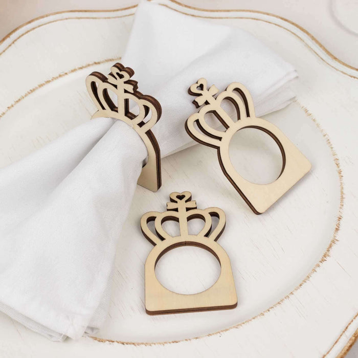 Wooden crown napkin holders on a decorative plate with white napkins.
