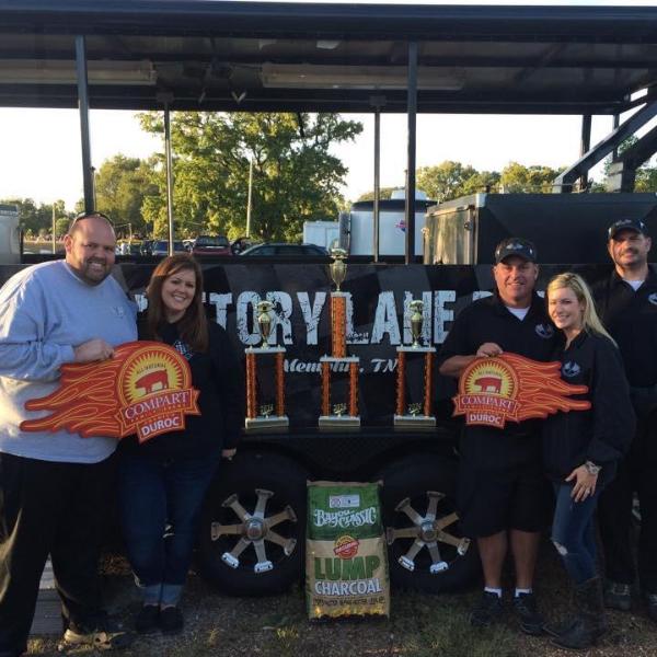 people with trophies showing bbq award using bayou classic charcoal