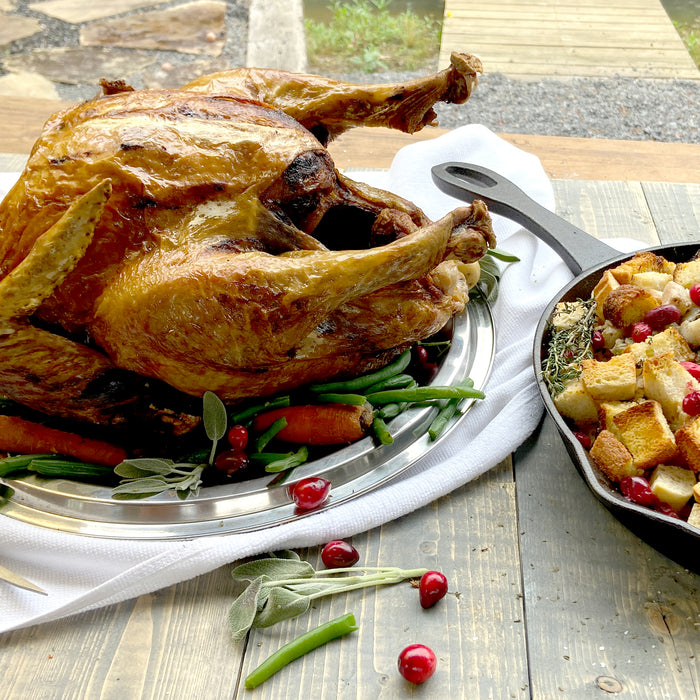 Cast Iron Skillet with cornbread dressing and a fried turkey on a platter in an outdoor setting