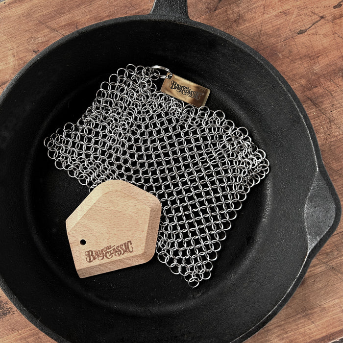 Chainmail scrubber and beech wood scrapper in a cast iron skillet