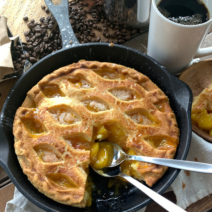 Cast Iron Skillet with partially eaten apple pie with spoons and coffee