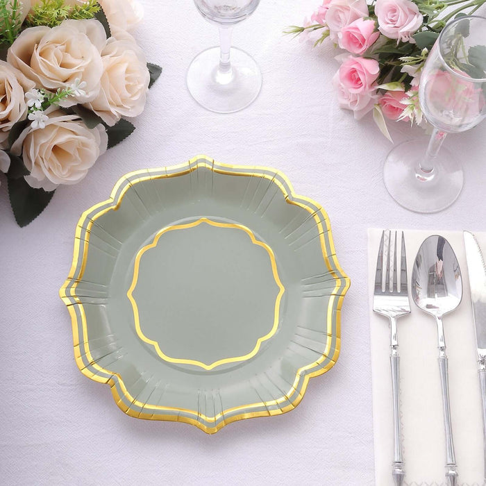 Elegant green plate with gold trim, set on a table with flowers and glassware.