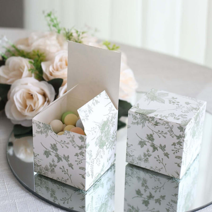 Decorative floral gift box with colorful candies inside on a reflective surface.