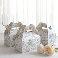 Floral patterned takeout boxes on a table with glasses and flowers.