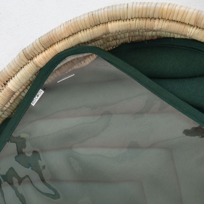 Close-up of a green fabric with a woven beige border on a white background
