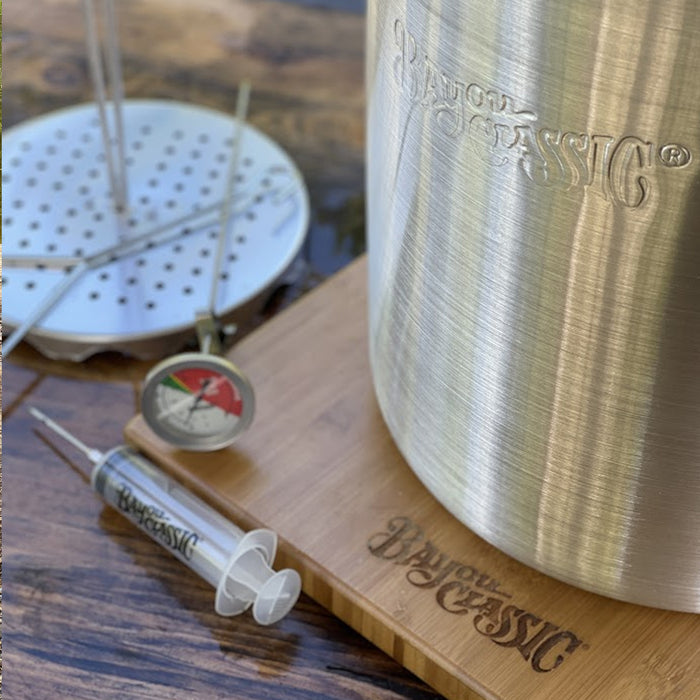 Close up image of aluminum turkey fryer with accessories on a wooden surface