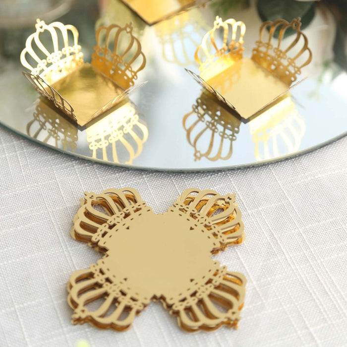 Gold crown-shaped coasters on a mirrored surface.