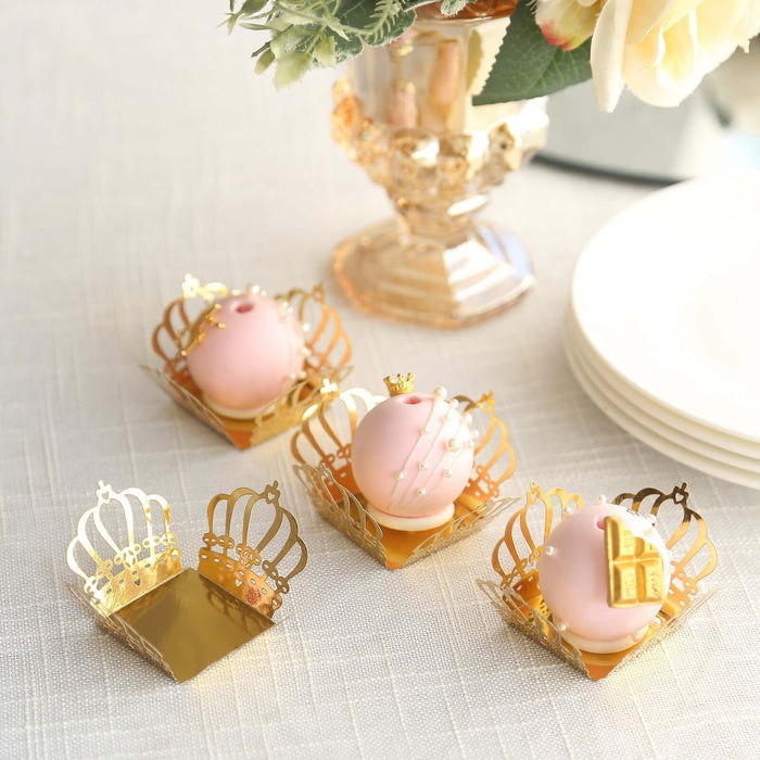 Gold crown-shaped dessert holders with pink sweets, elegantly arranged on a table.