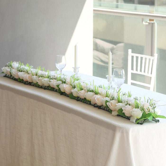 Elegant floral table runner with white roses and greenery for event decor.