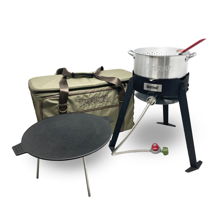 A camper's combo kit including a black steel frame cooker, aluminum fry pot and basket, cast iron discada, and gear bag on a white background