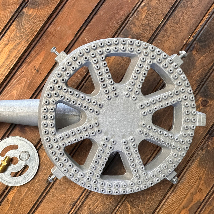 Cast iron banjo burner with orifice, air shutter, and spring on a wood surface.