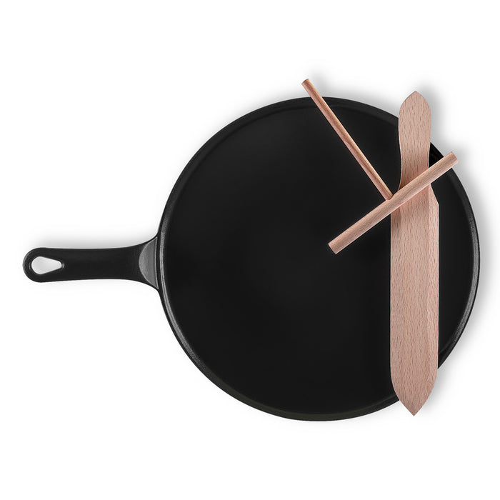 Black frying pan with wooden spatulas on a white background