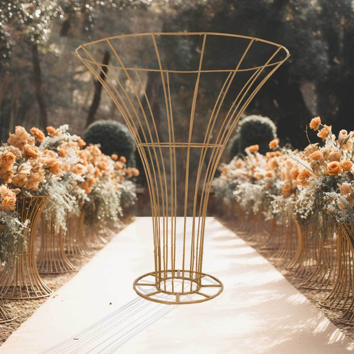 Gold wire vase stand surrounded by floral arrangements in a garden setting.