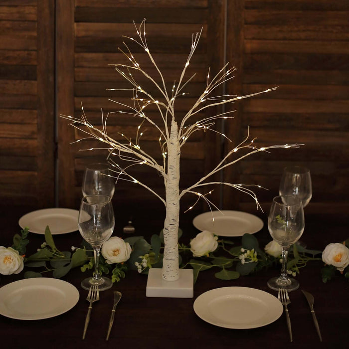 Decorative lighted birch tree centerpiece for dining table setting.