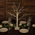 Decorative lighted birch tree centerpiece for dining table setting.