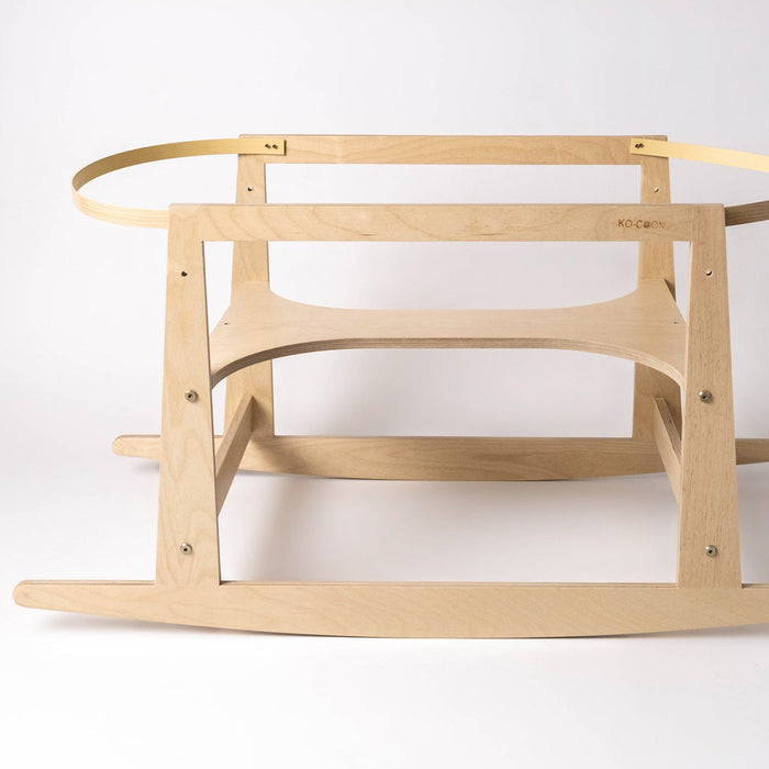 A birch wood Moses basket stand that has been designed to transform into a rocking horse, viewed from a side angle against a white background.