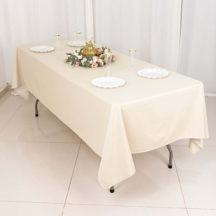 Elegant beige tablecloth on a dining table set for a celebration with floral centerpiece.