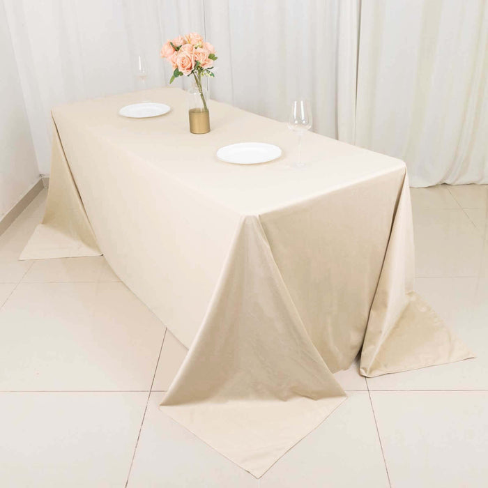 Elegant beige tablecloth draped over a table set with plates and flowers.