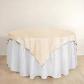 Round table with beige tablecloth and white skirt on a plain background.