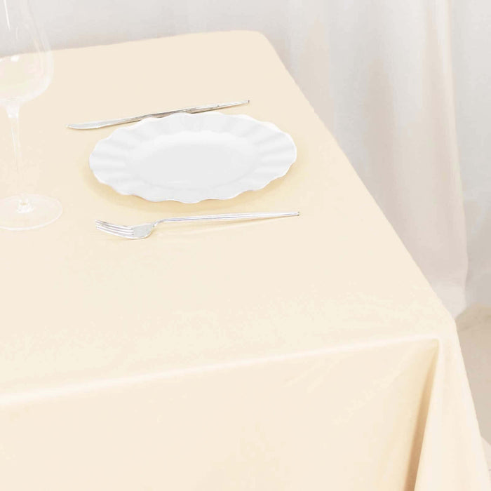 Elegant white plate on a beige tablecloth with silver cutlery.