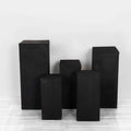 Black geometric display pedestals in various heights on a plain background.