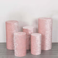 Set of five pink velvet pedestals in varying heights on a gray surface.