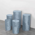 Set of five blue velvet pedestals in varying heights on a neutral background.