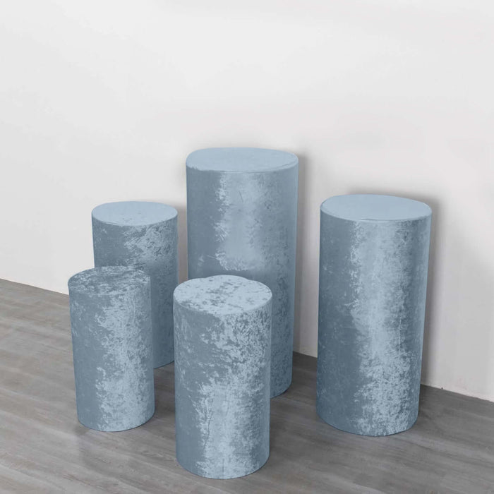 Set of five blue velvet pedestals in varying heights on a neutral background.