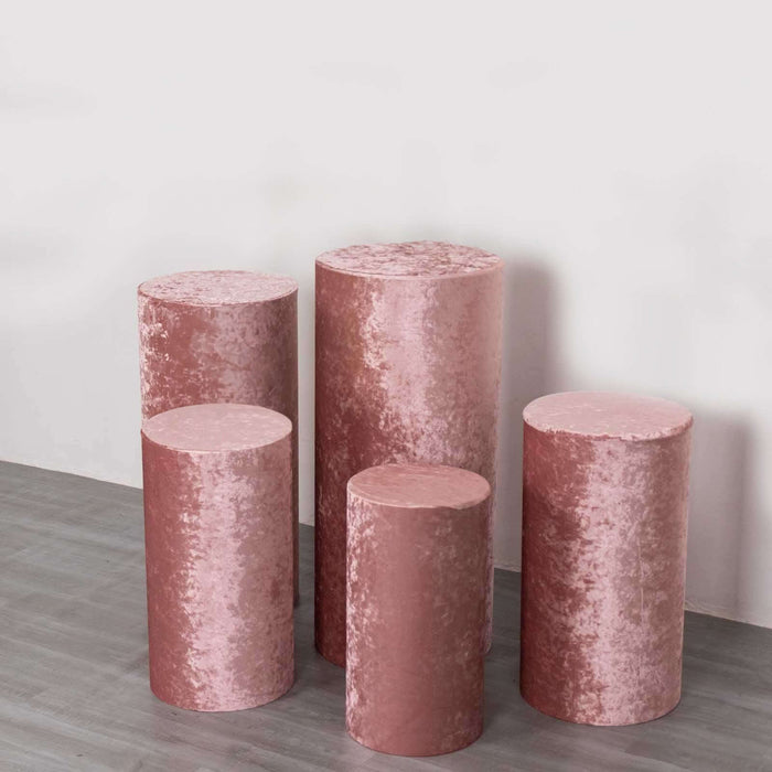 Set of five pink velvet display pedestals in varying heights.