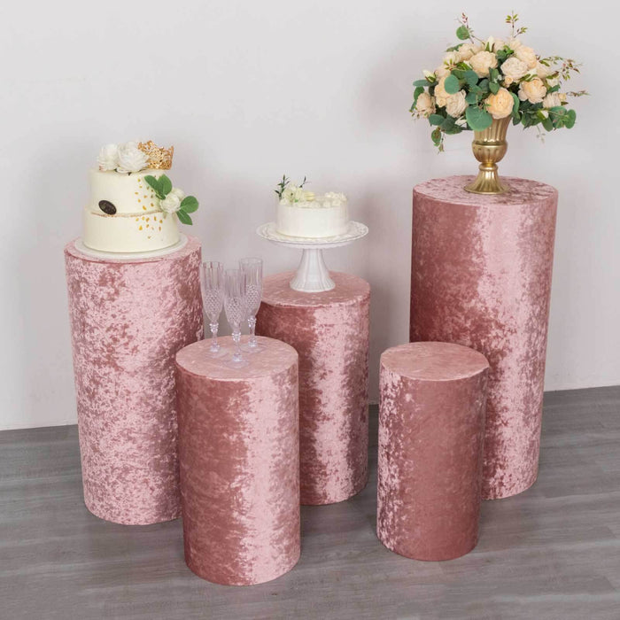 Pink velvet pedestal display tables with floral arrangements and a cake.
