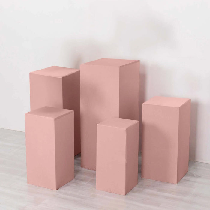 Pink display pedestals in various heights on a plain background.