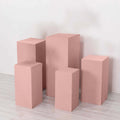 Pink display pedestals in various heights on a plain background.
