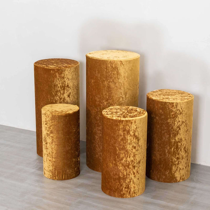 Set of five golden velvet cylindrical stools in varying heights.