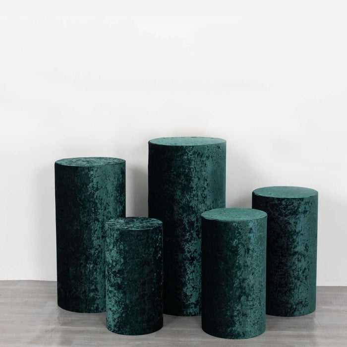 Green velvet pedestals in varying heights on a plain backdrop.