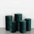 Green velvet pedestals in varying heights on a plain backdrop.