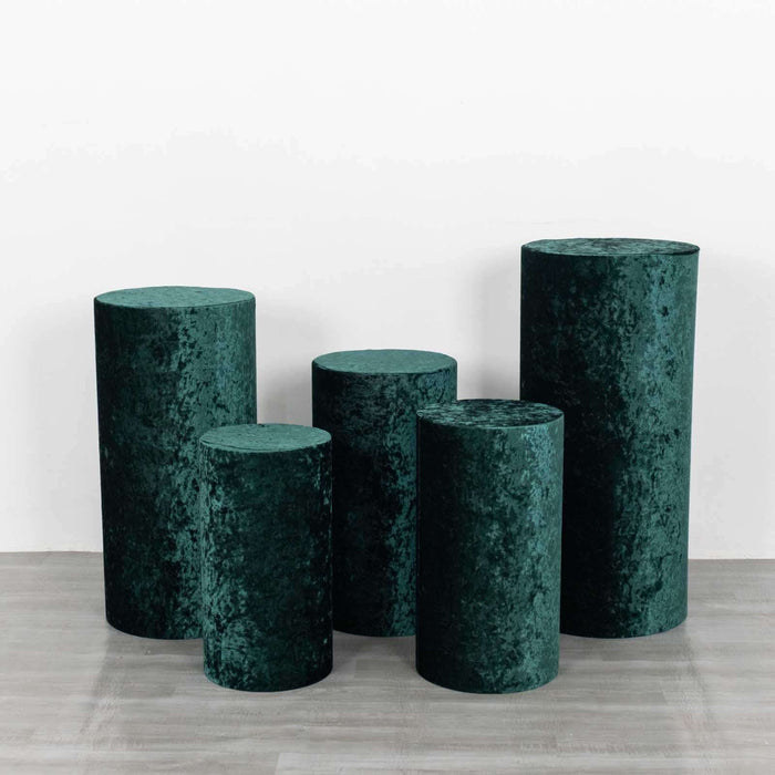 Green velvet cylindrical pedestals in various heights on a white background