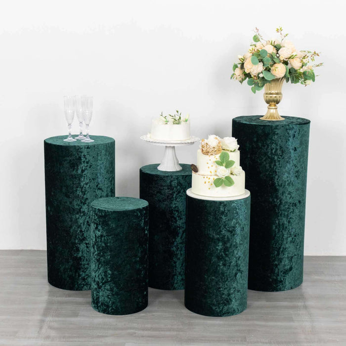 Green velvet display pedestals for events with decorative cake and floral arrangements.