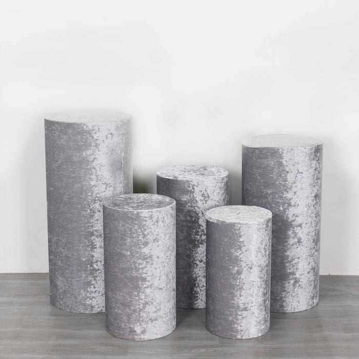 Set of five decorative gray pedestals in various heights and shapes.