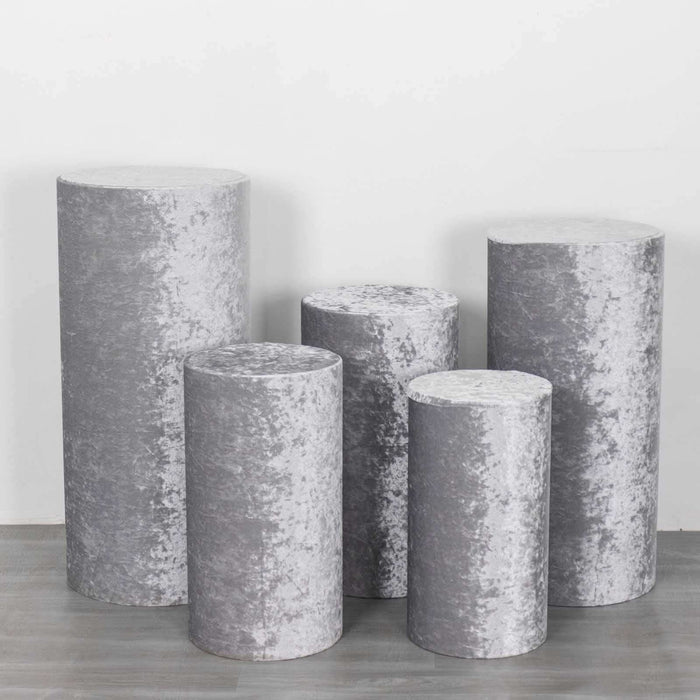 Set of five grey velvet pedestals in varying heights for display purposes.