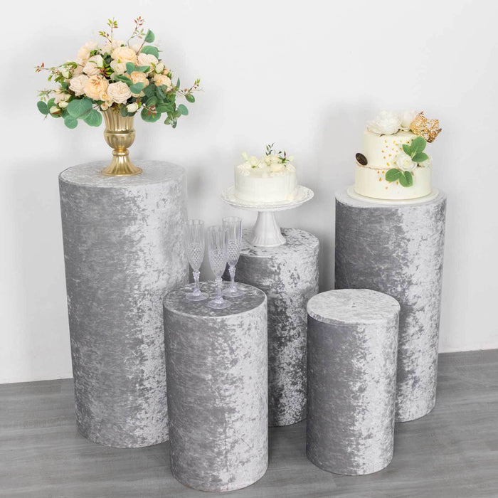Decorative gray pedestals with floral arrangement and cakes for event display.