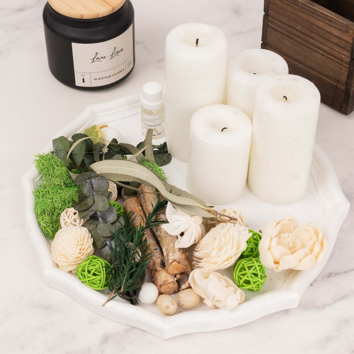 Decorative tray with candles, greenery, and natural elements on a marble surface.