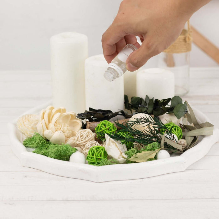 Decorative tray with candles and natural elements, adding essential oil.