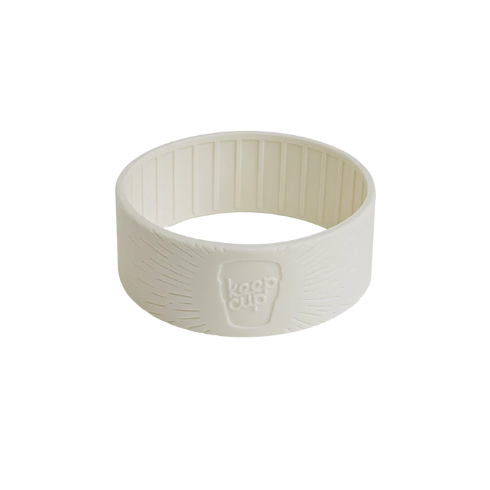 KeepCup silicone band in a cream or off-white colour, shown at a slight angle against a plain white background, featuring the embossed KeepCup logo and textured grip pattern on the exterior with vertical ridges on the interior.