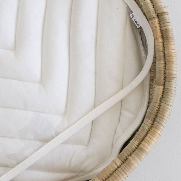 Close-up of a clear changing mat on top of a changing padding in a lala palm changing basket on a plain background